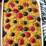 Un plato de avena al horno con arándanos y frambuesas encima.