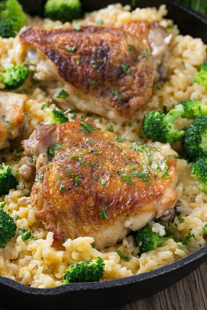 Muslos de pollo servidos sobre arroz con queso y brócoli.