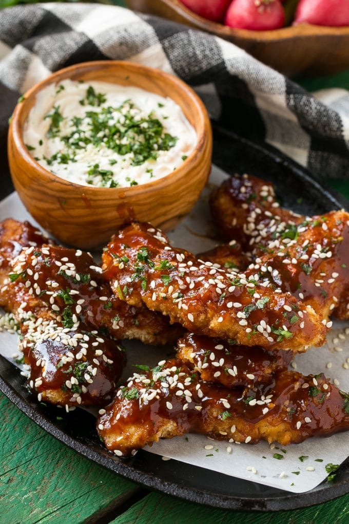 Palitos de pollo al horno servidos con salsa de sésamo.