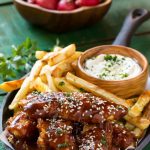 Estos palitos de pollo al horno con sésamo se rocían con una salsa asiática dulce y picante y se sirven con papas fritas y una salsa cremosa de sésamo.  ¡Una comida completa en 30 minutos con menos culpa!  Anuncio de #FarmToFlavor