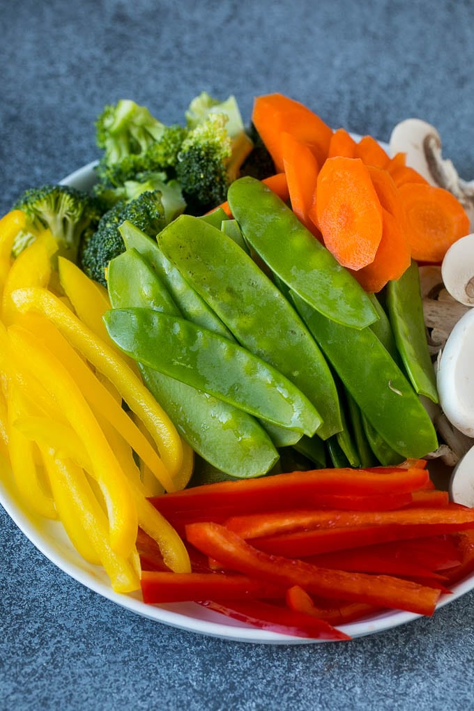 Pimientos, guisantes, zanahorias, champiñones y brócoli en un plato.
