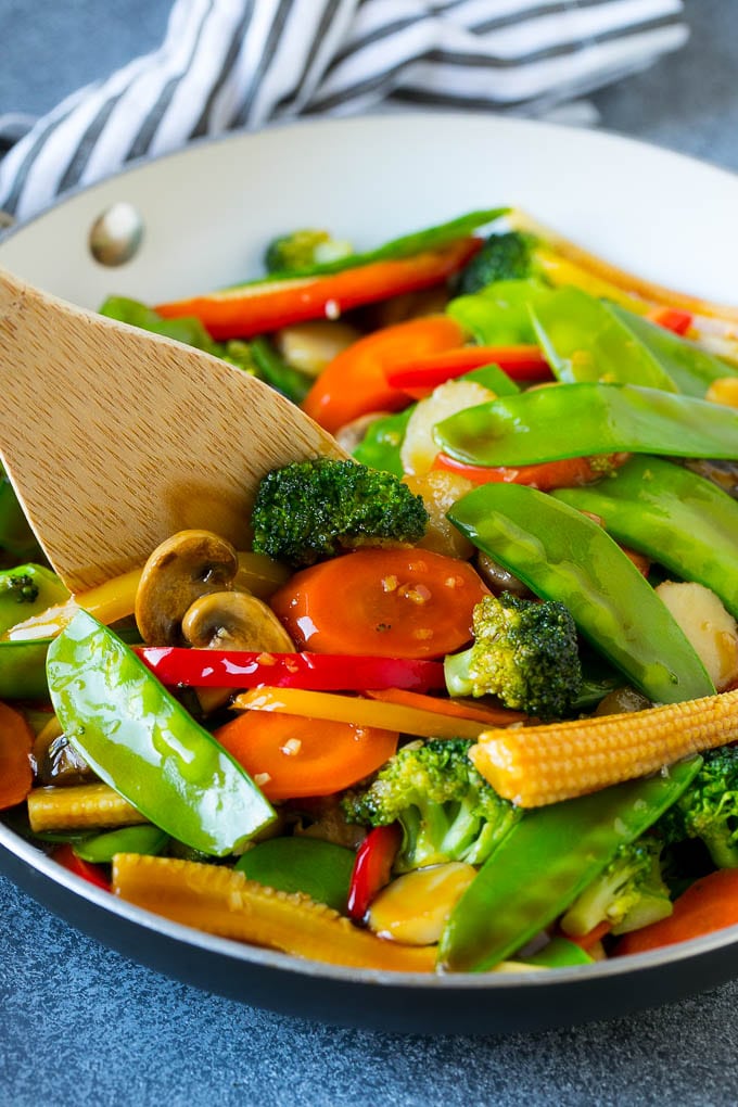 Una espátula de verduras salteadas con zanahorias, guisantes y brócoli.