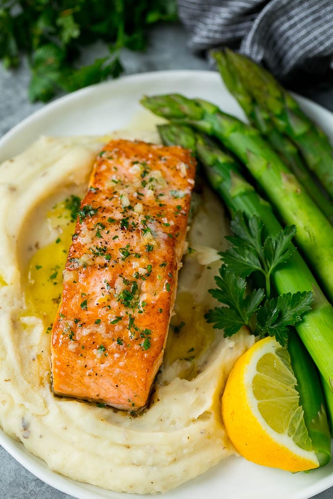 Filete de salmón braseado servido con puré de papas y espárragos.