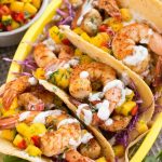 Tacos de camarones con salsa de mango dulce y picante y salsa cremosa de cilantro y lima.