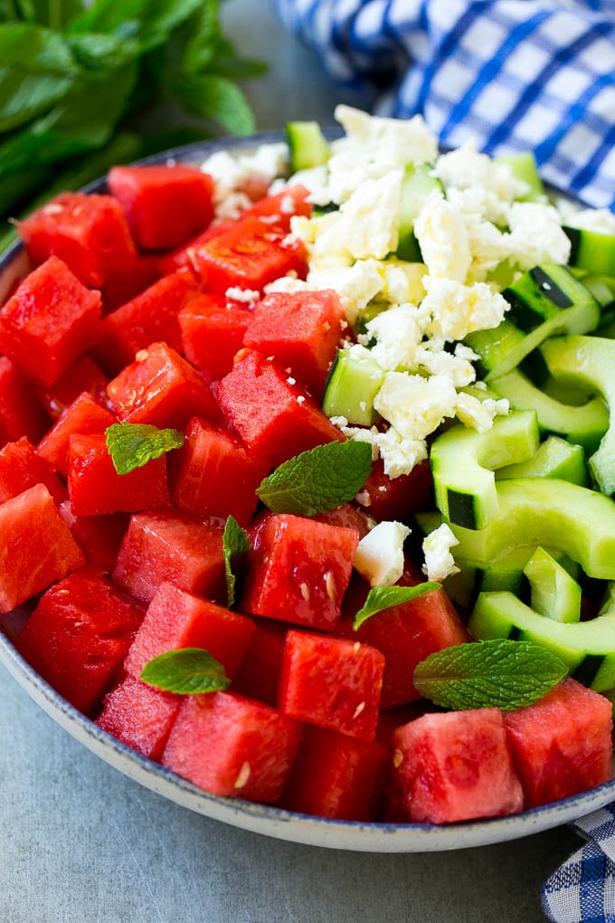 Un tazón de sandía, pepino, queso feta y hojas de menta cubierto con salsa de lima.