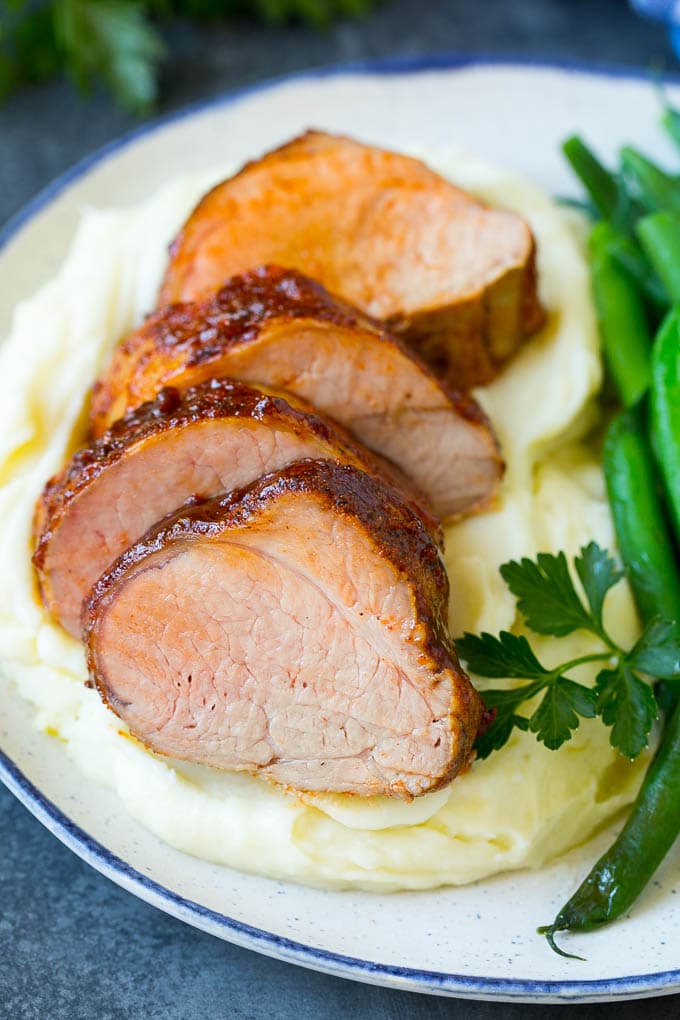 Lomo de cerdo ahumado en lonchas servido con puré de papas y verduras.