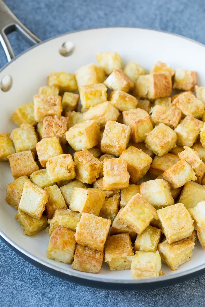 Cubitos de tofu salteados crujientes en una sartén.