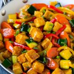 Tofu salteado con pimientos, zanahorias y calabacín en salsa de miel y ajo.