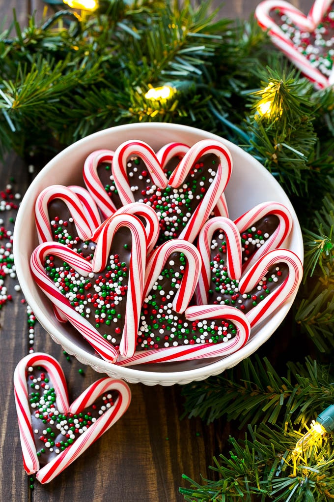 Un tazón de corazones de bastón de caramelo adornado con chispas festivas.