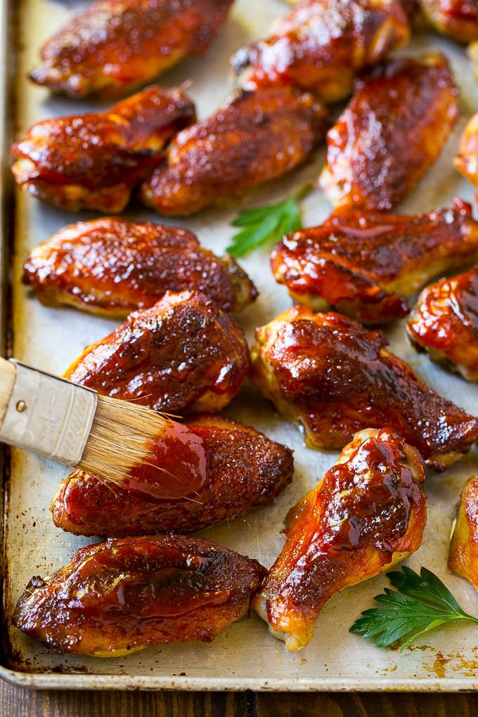 Salsa barbacoa cepillada sobre un plato de alitas de pollo ahumadas.