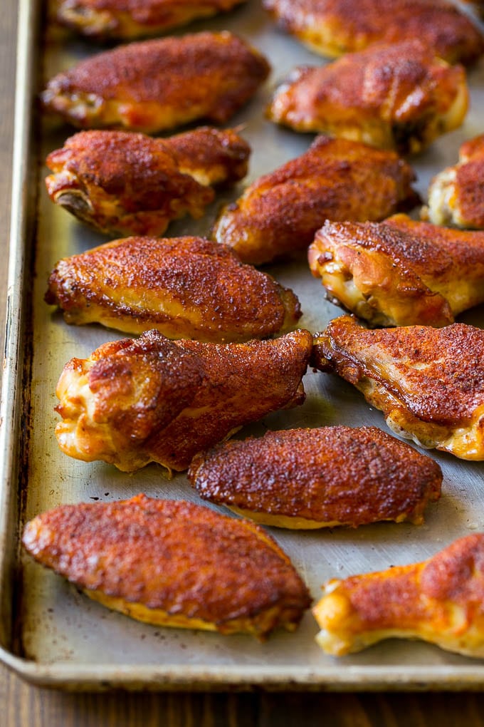 Alitas de pollo ahumadas cubiertas con especias se frotan en una bandeja para hornear.