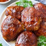 Un plato de muslos de pollo ahumado cubierto de especias y salsa barbacoa.