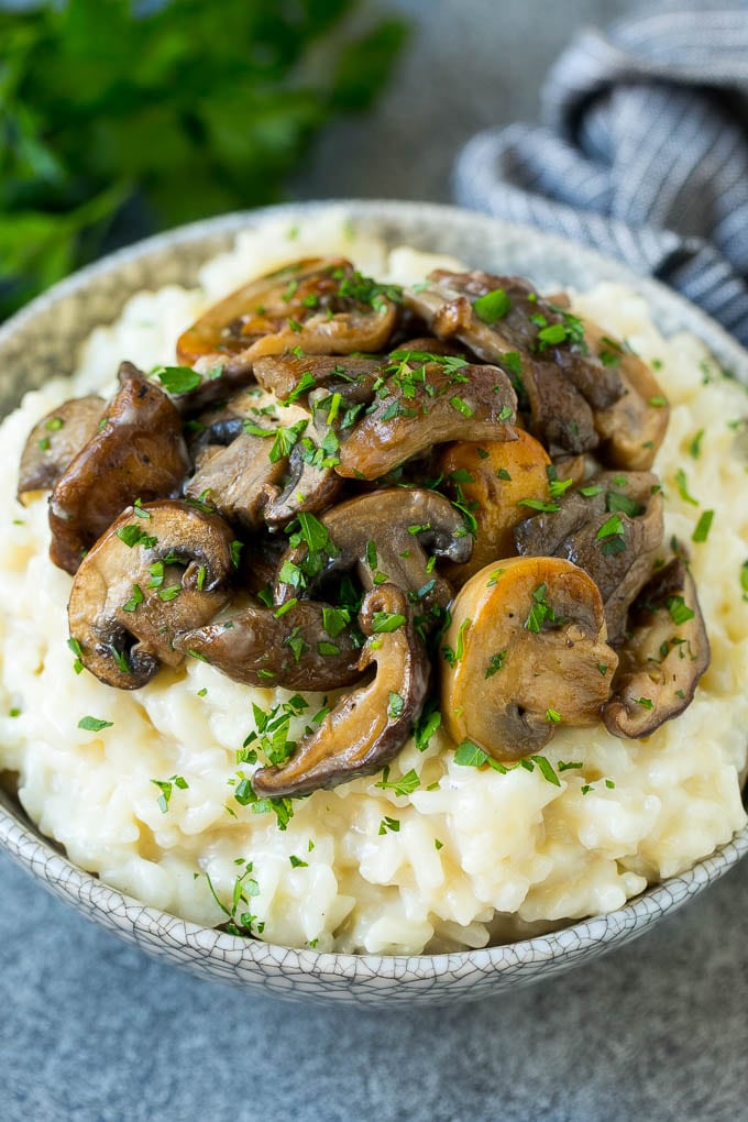 Un plato de risotto de champiñones cubierto con champiñones al ajillo con mantequilla.