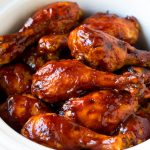 Muslos de pollo en olla de cocción lenta recubiertos con salsa barbacoa en una olla de cocción lenta.