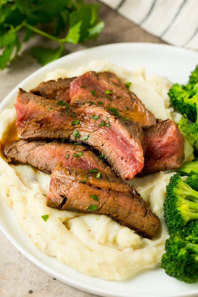 Bife de lomo marinado servido con puré de papas y brócoli.