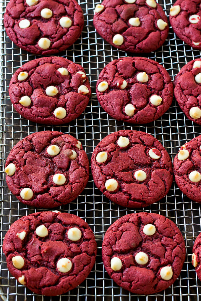 Receta de galletas de terciopelo rojo | Galletas de chocolate blanco de terciopelo rojo | Galletas Red Velvet Cake Mix #redvelvet #cookies #whitechocolate #christmas #dinneratthezoo Galletas de terciopelo rojo con chispas de chocolate blanco en una rejilla para enfriar.
