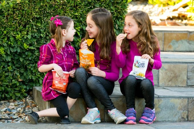 Los niños comen bolsas de papas fritas.