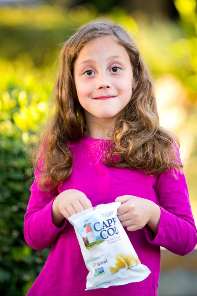 Una niña sosteniendo una bolsa de papas fritas.