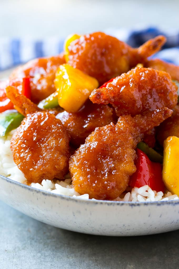 Langostinos agridulces con piña y pimientos, servidos sobre arroz.