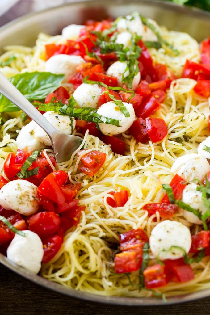 Una cacerola de pasta caprese con cabello de ángel, aceite de oliva, albahaca fresca, tomates y mozzarella.