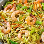 Una cacerola de fideos chow mein de camarones con verduras.