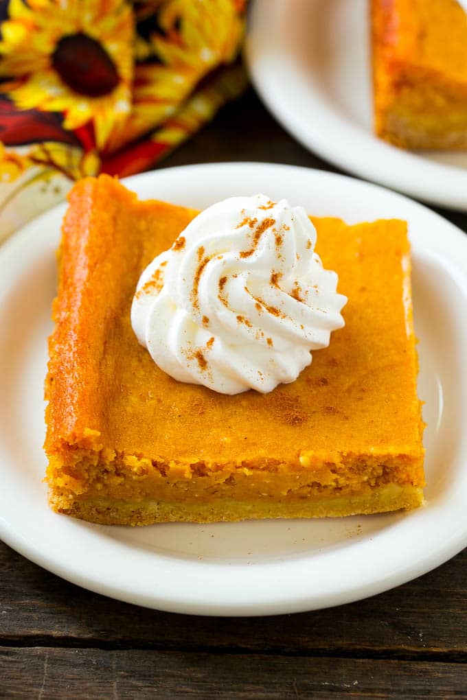 Una rebanada de pastel de mantequilla de calabaza pegajosa cubierta con crema batida.