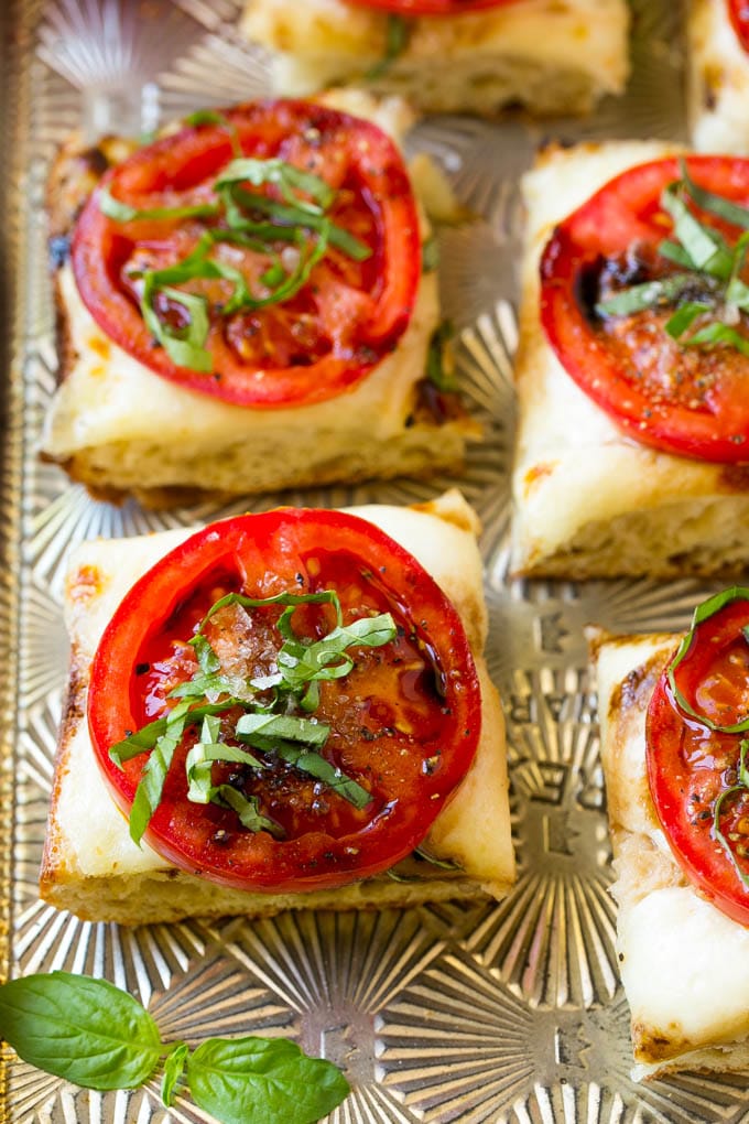 Receta de pan Caprese | Pan de tomate | Pan de queso #caprese #capresebread #paintomate #cheesebread #aperitivo #dinneratthezoo Pan cortado en cuadritos aderezado con mozzarella derretida, rodajas de tomate, albahaca y glaseado de vinagre balsámico.