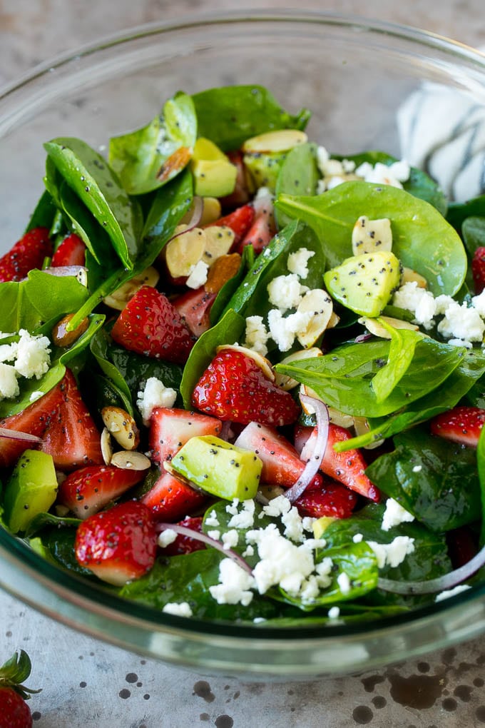 Receta de ensalada de espinacas y fresas | Ensalada de Fresas | Ensalada de espinacas # espinacas # ensalada # fresas # aguacate #dinneratthezoo Un tazón de ensalada de fresas y espinacas con aderezo de semillas de amapola, queso feta y aguacate en rodajas.