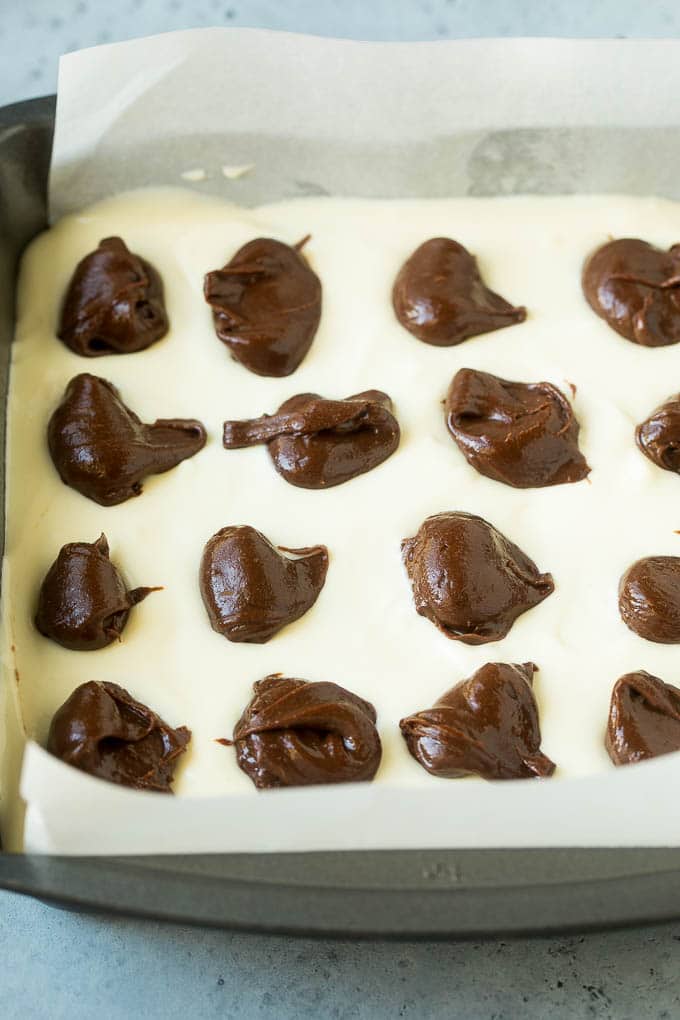 Brownies cubiertos con una capa de tarta de queso y mechones de masa de chocolate.