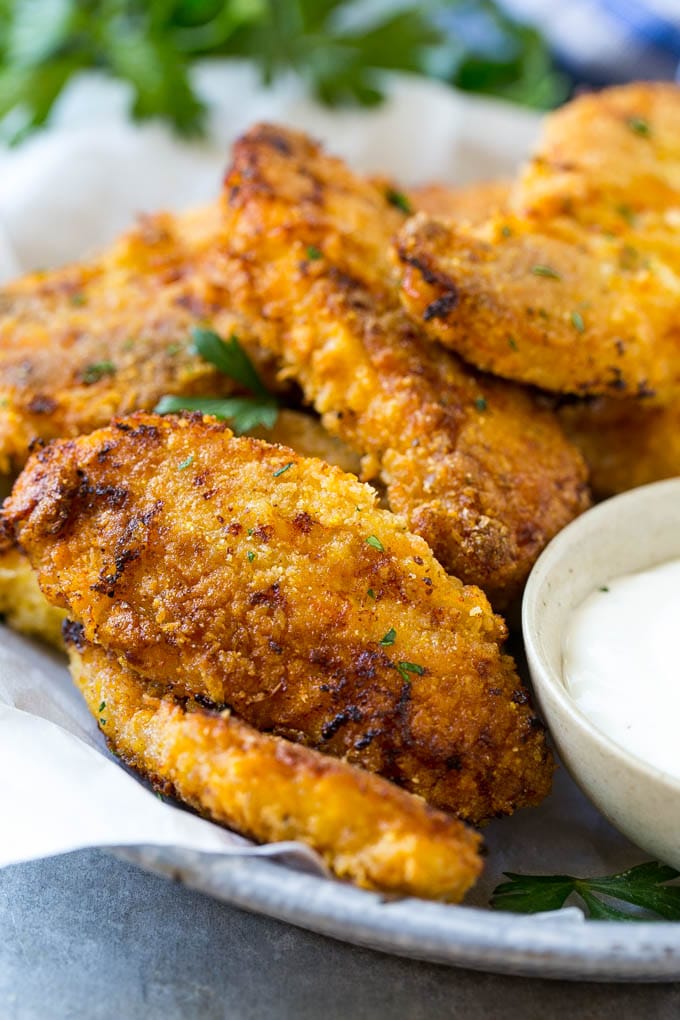 Palitos de pollo frito al horno en un plato con una guarnición de salsa ranch.