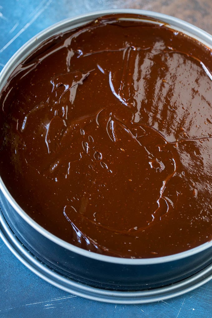 Una capa de ganache de chocolate sobre una tarta de queso Oreo.